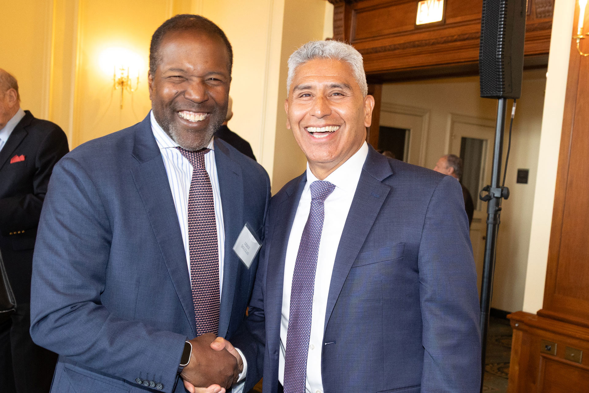 Two people shaking hands and looking towards the camera