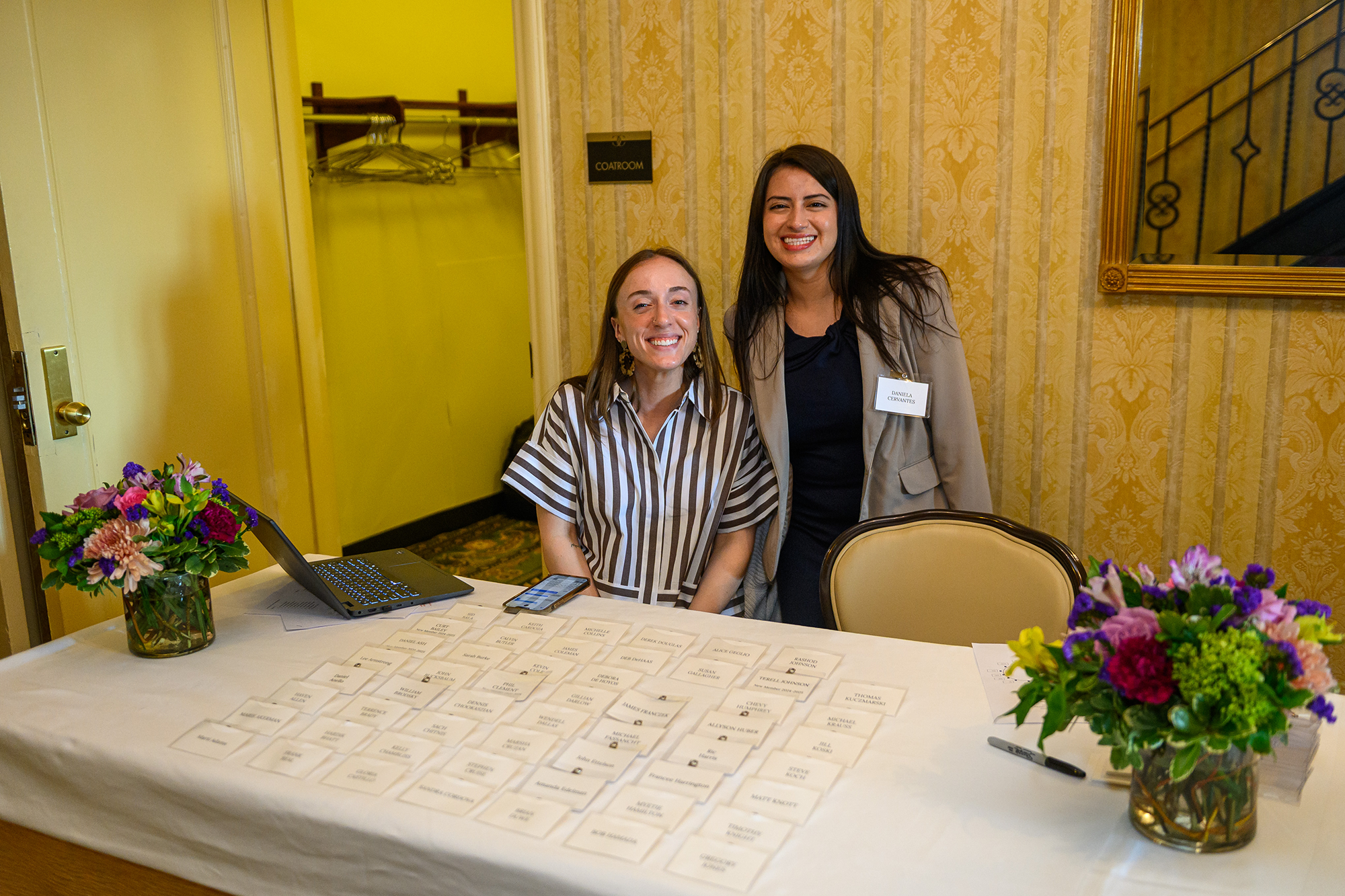 Two people stand behind a table filled with name tags