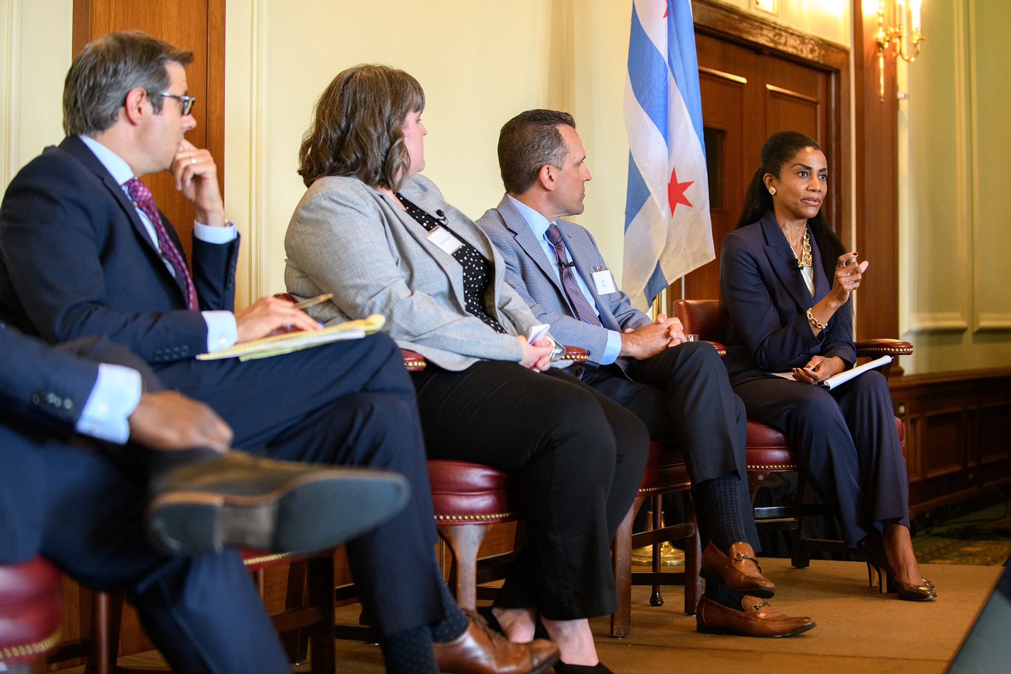 Four people sitting on stage while one speaks
