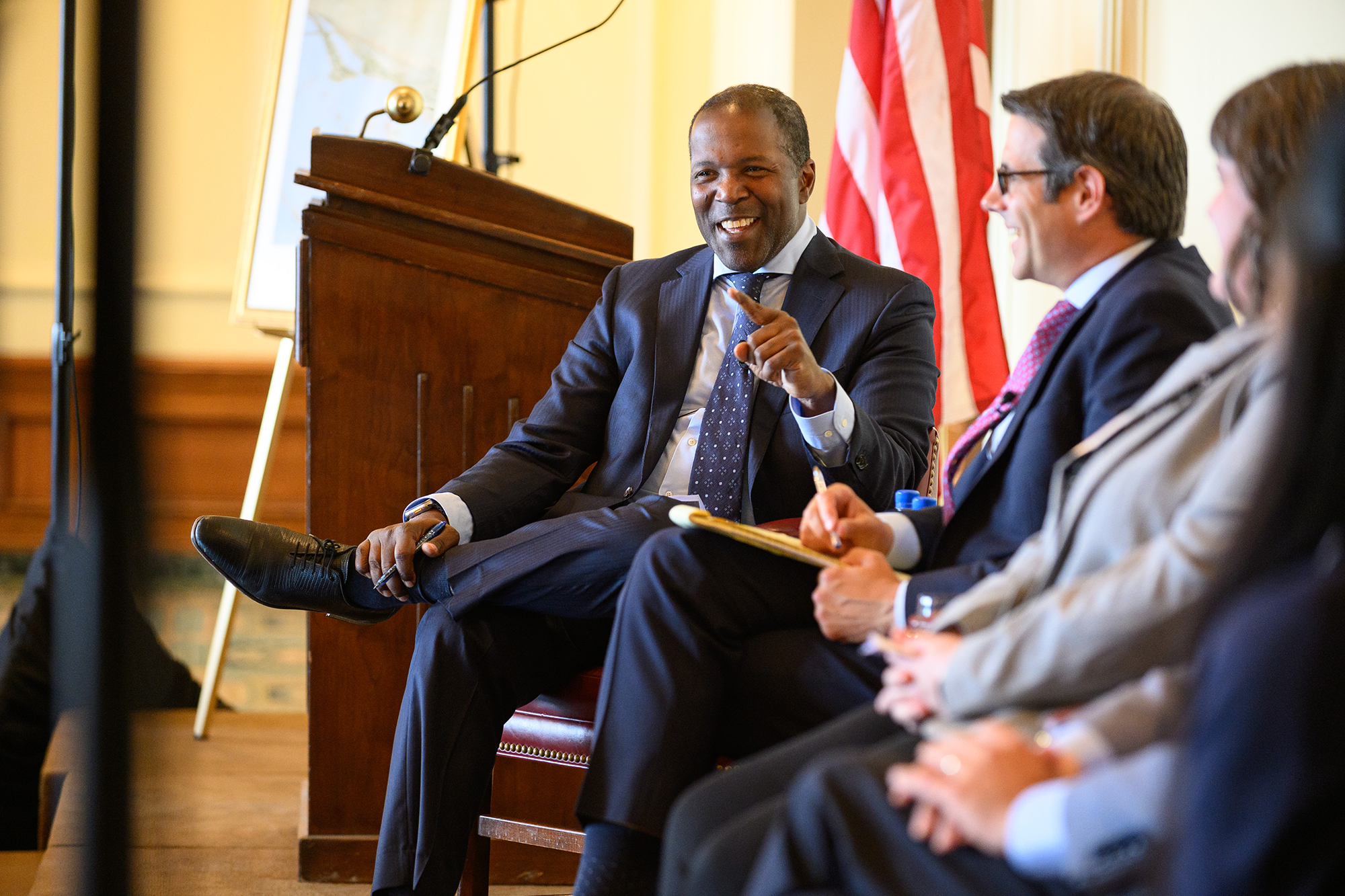 A person laughs while sitting on stage