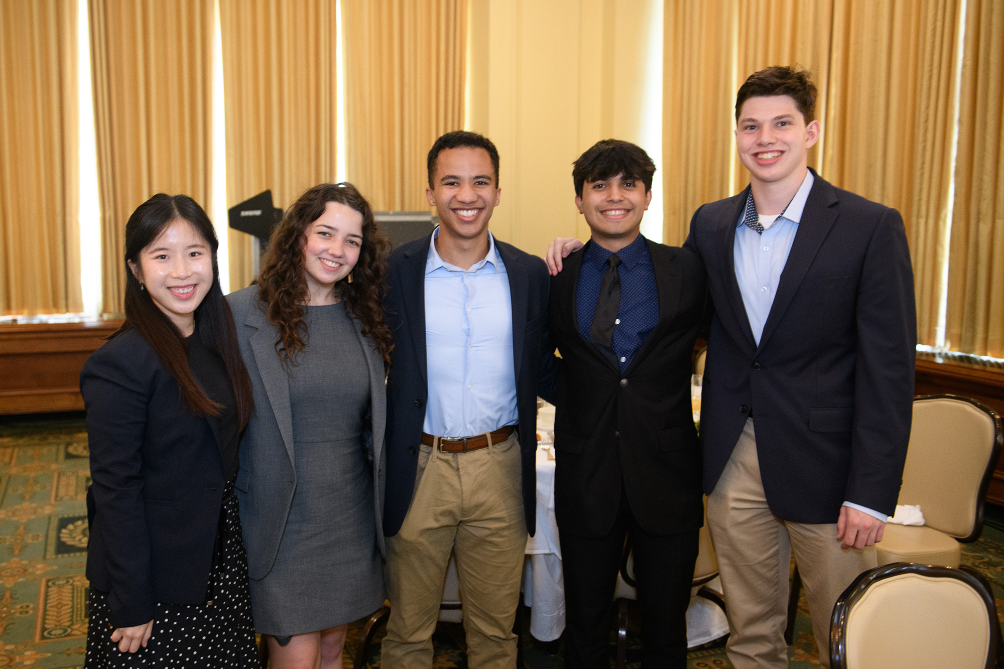 Five people stand together, facing the camera