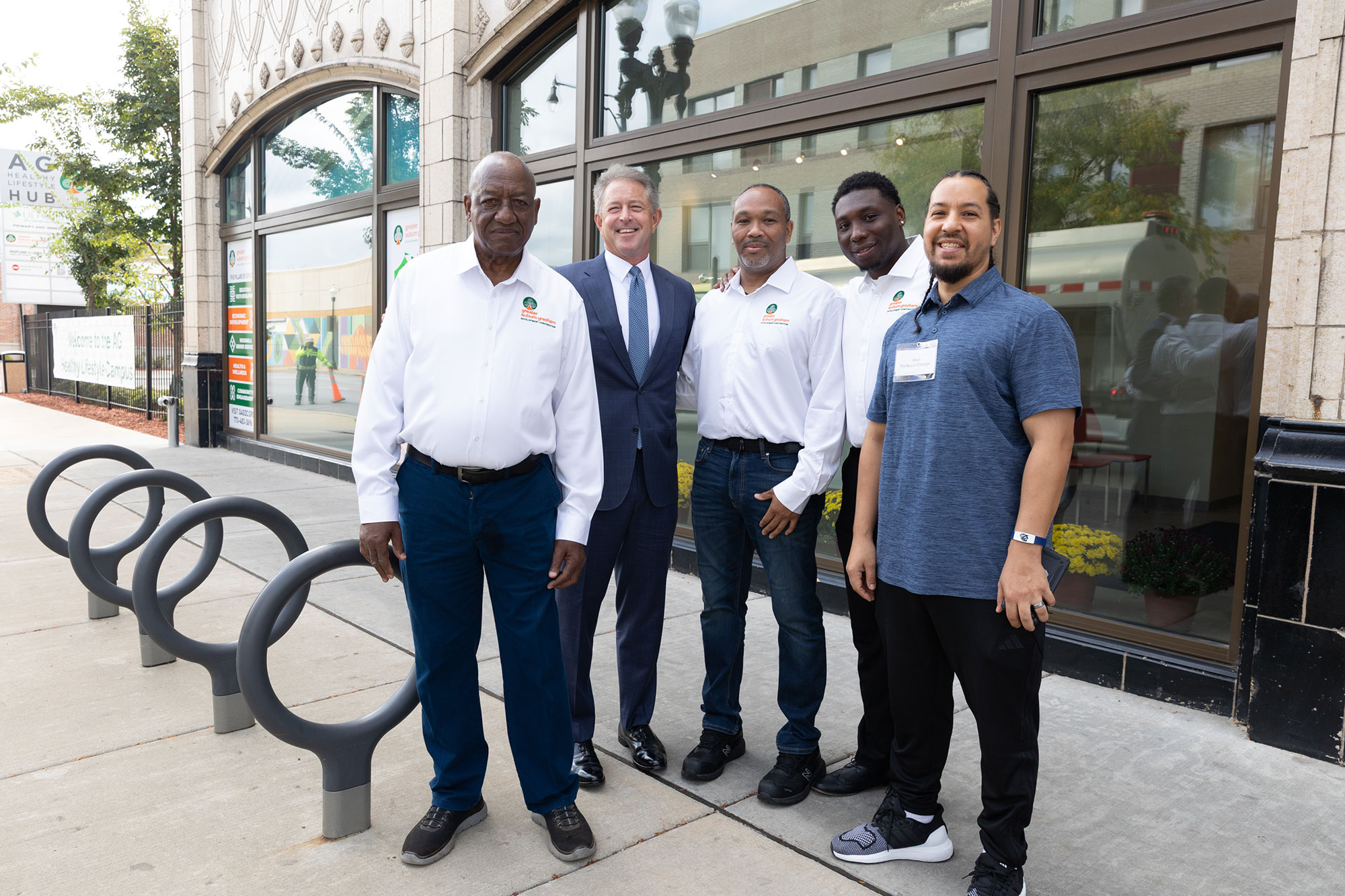 Five people stand in front of a glass window of a building