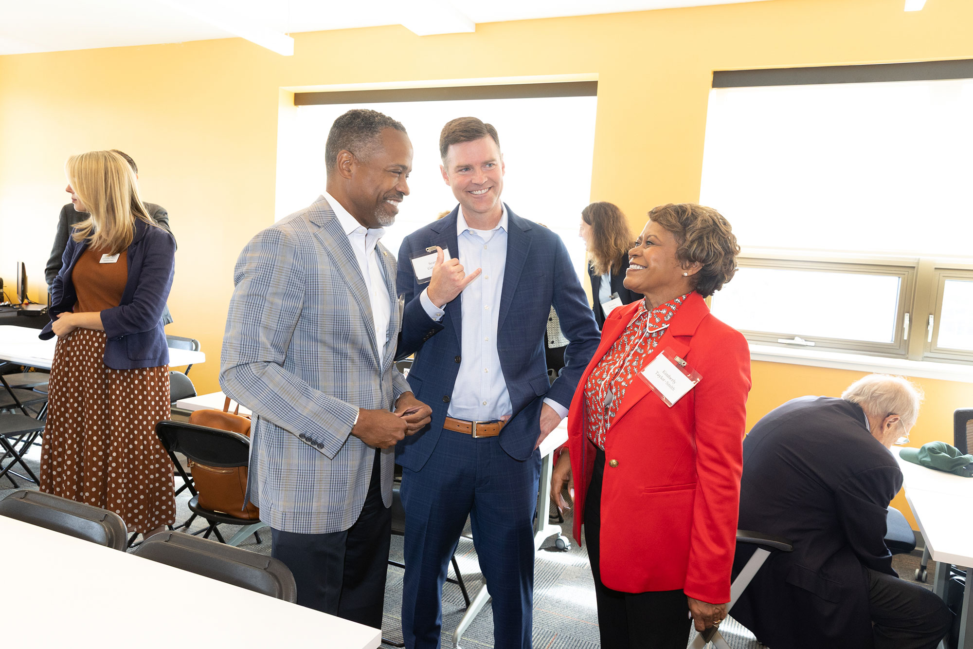 Three people stand and talk while smiling
