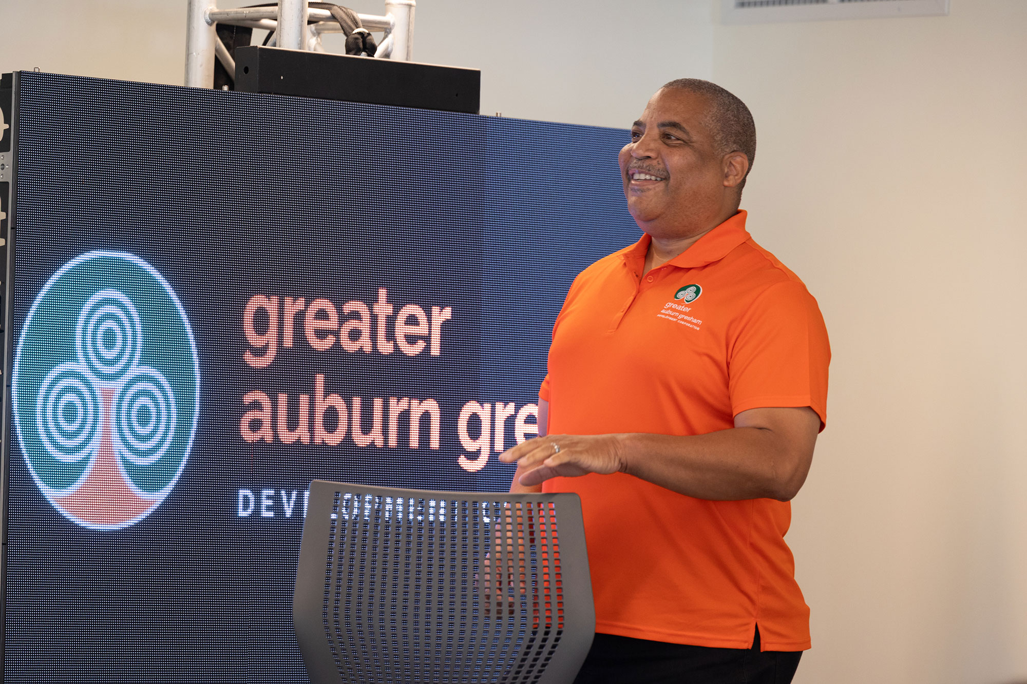 A person speaks behind a podium with a TV screen behind them