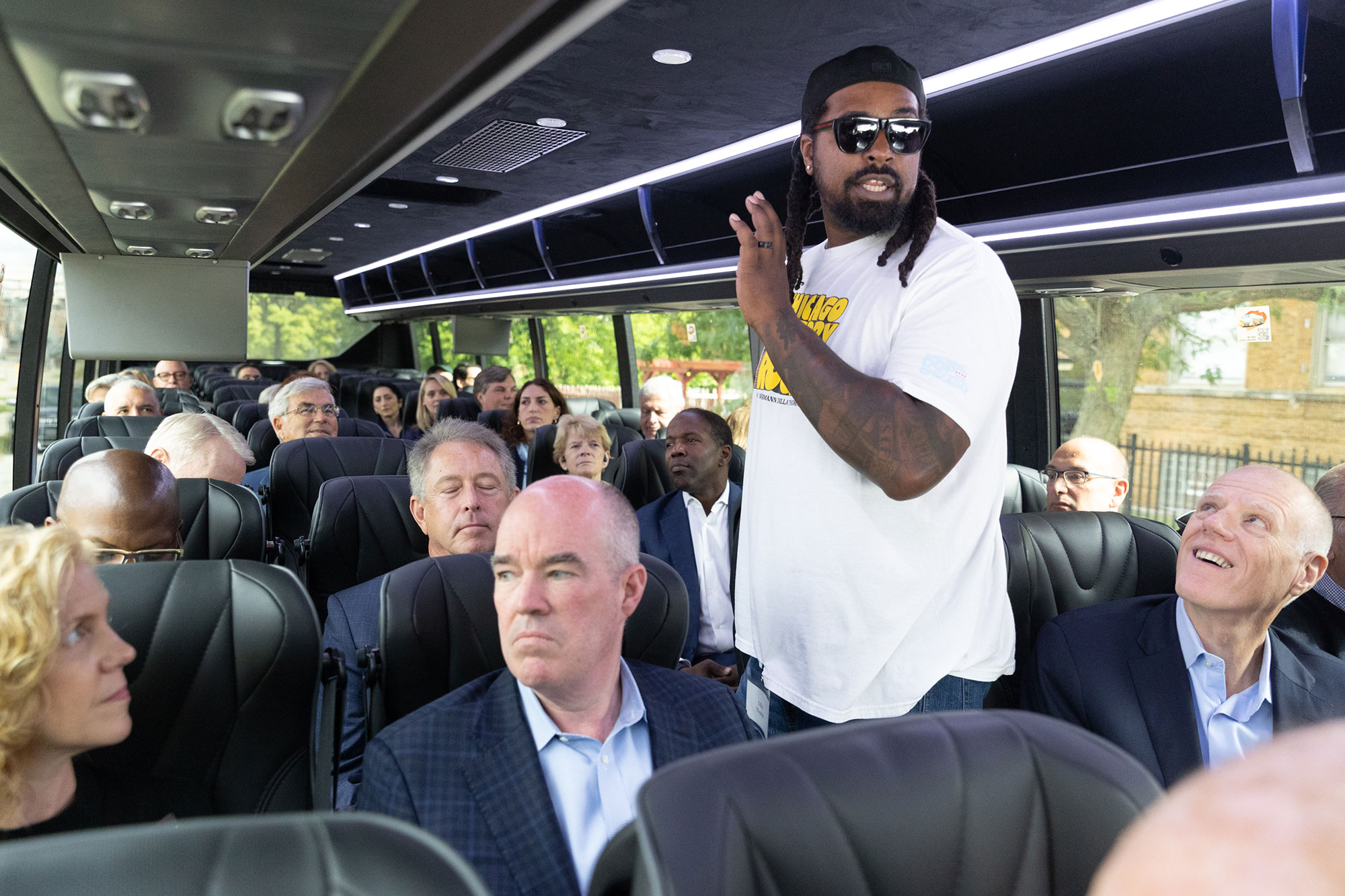 A person speaks to people sitting on a bus