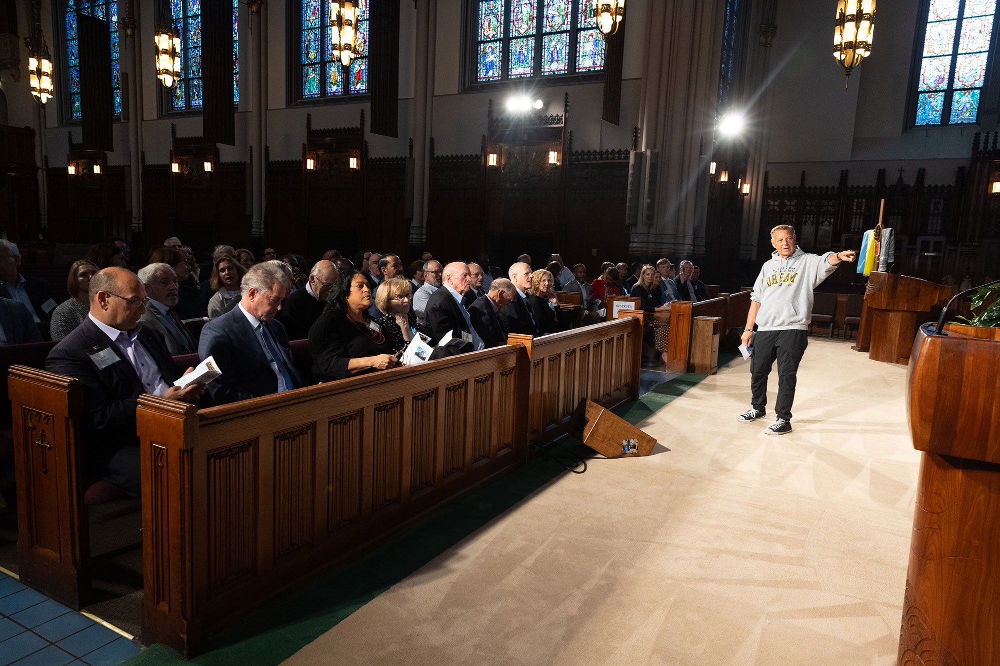 A person speaks to a large group of people sitting in church pews