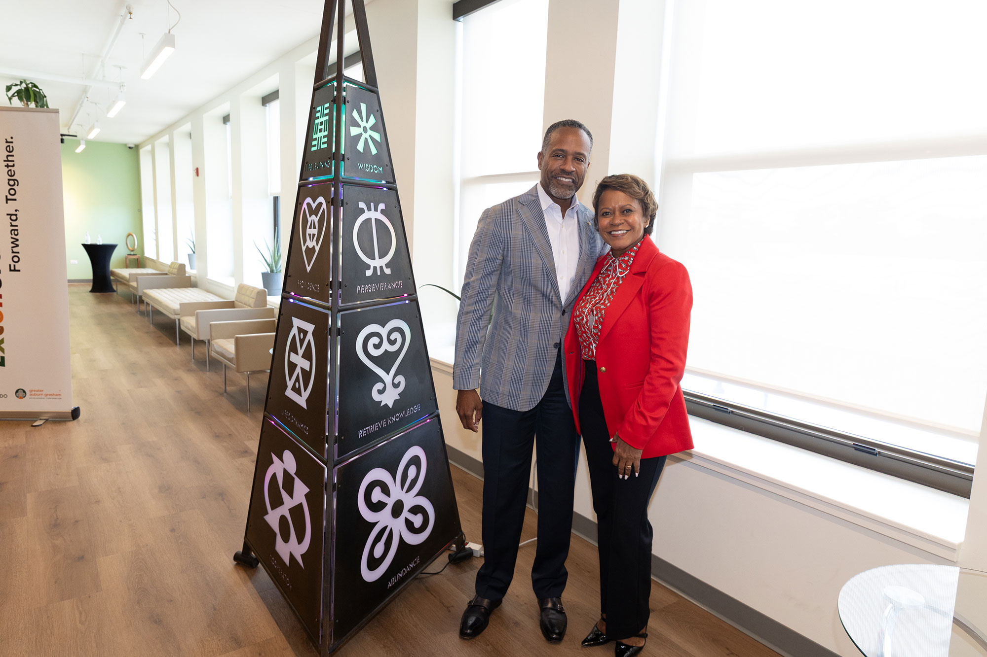Two people smile and pose in front of a pyramid structure