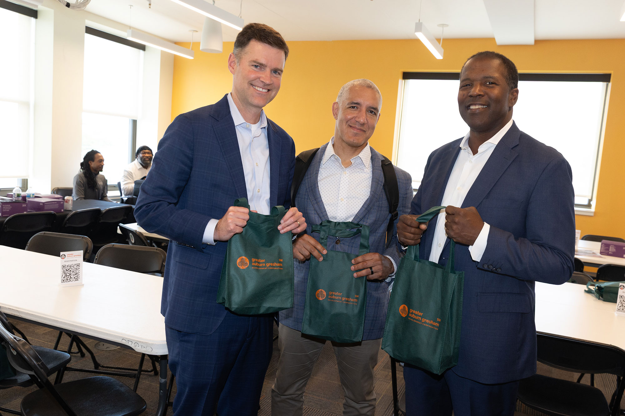 Three people stand and pose while holding canvas tote bags