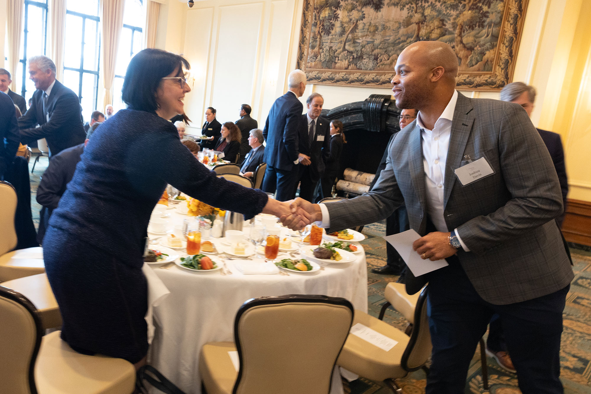 Two people reach across a table to shake hands