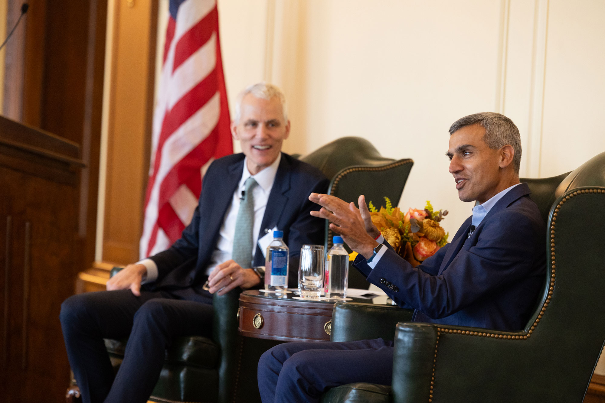 Two people talk while sitting in chairs on-stage