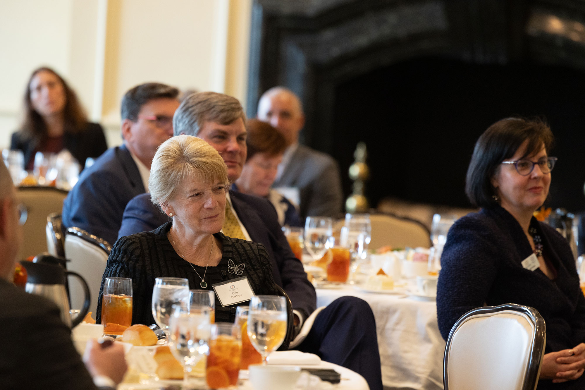 People listen while sitting at tables in the audience