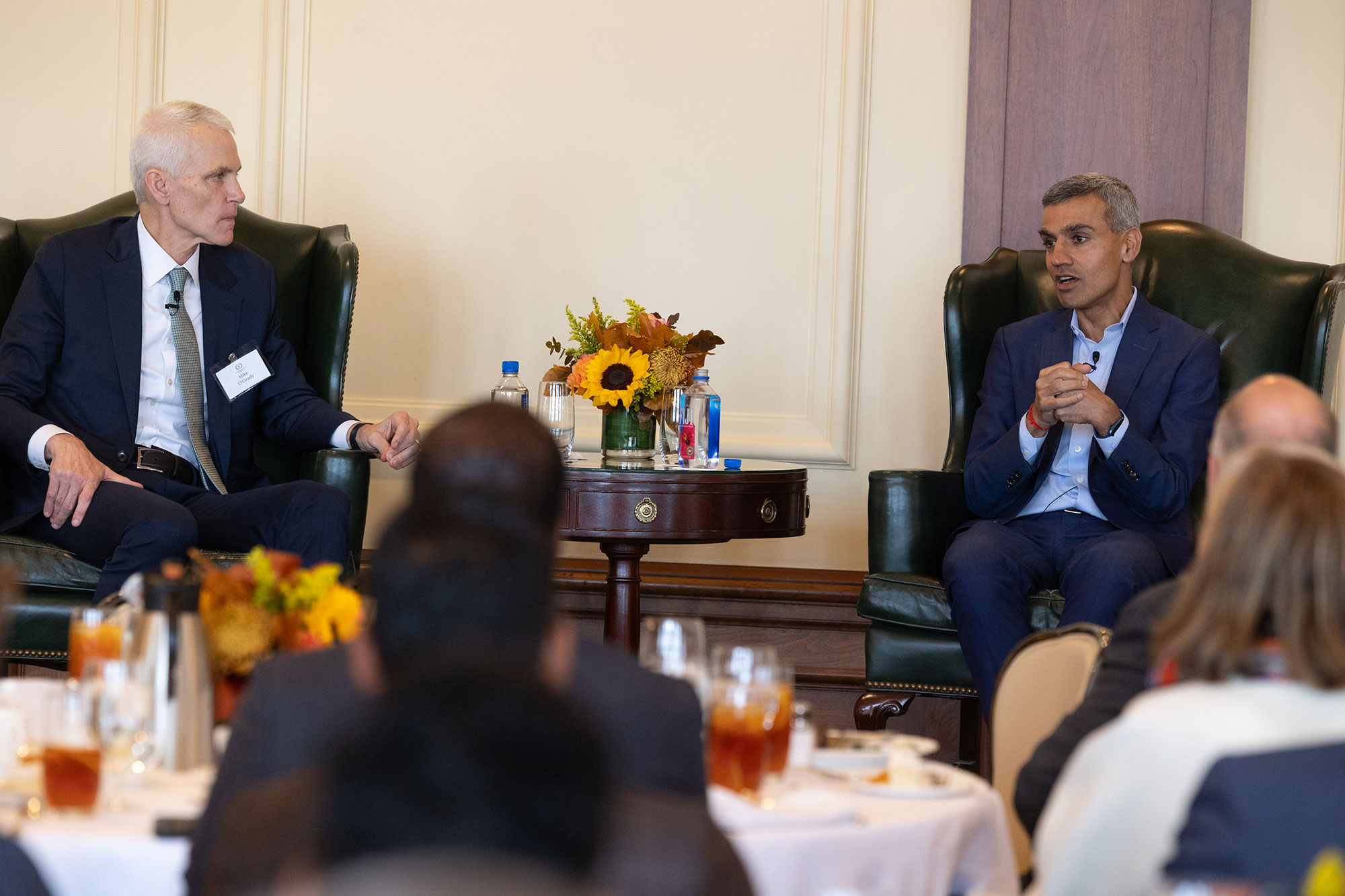 Two people sit in chairs on stage