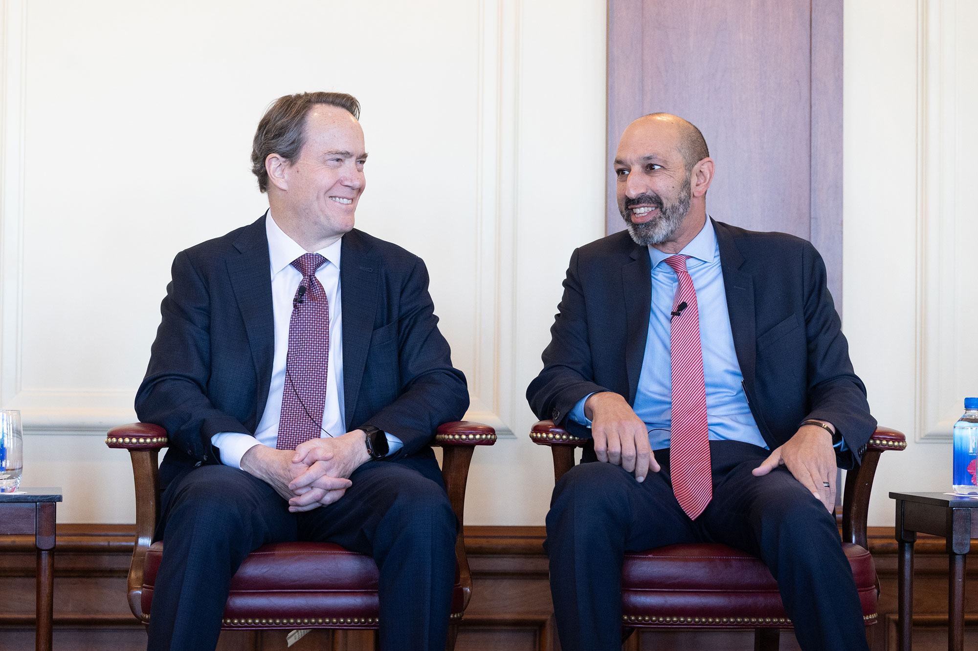 Two people sit in chairs on stage