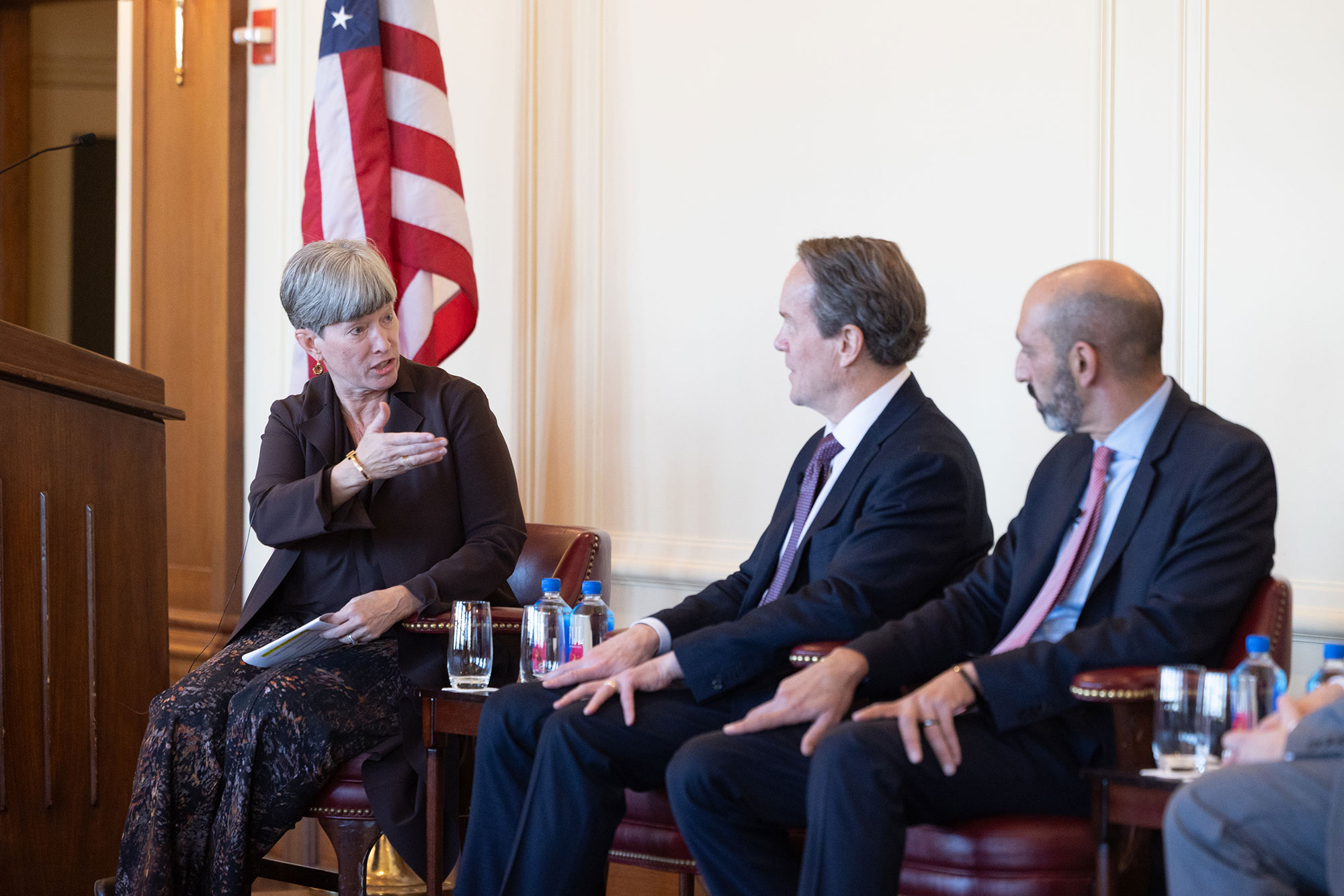 3 people sit in chairs on stage