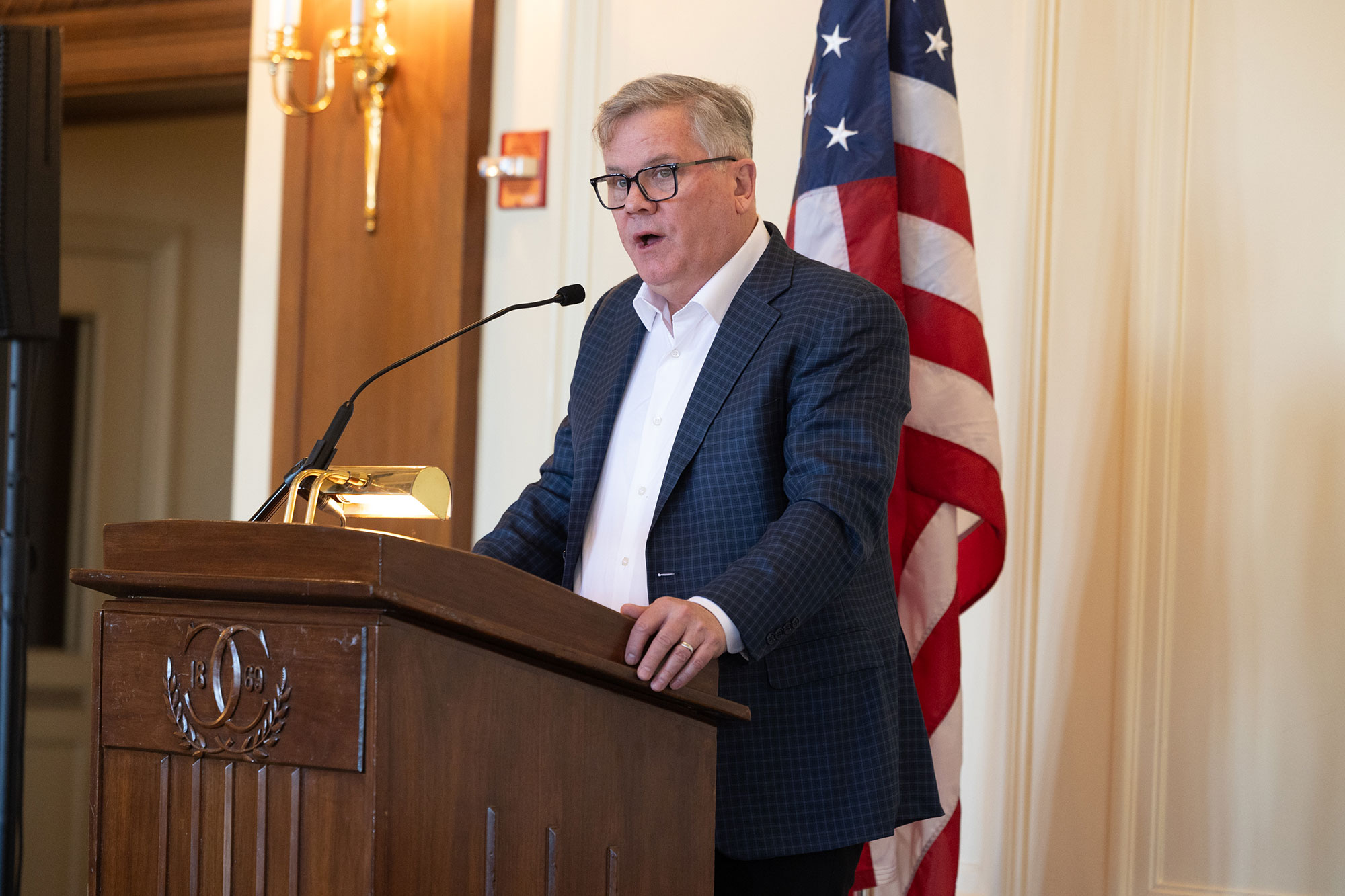 A person stands while talking into a microphone behind a podium
