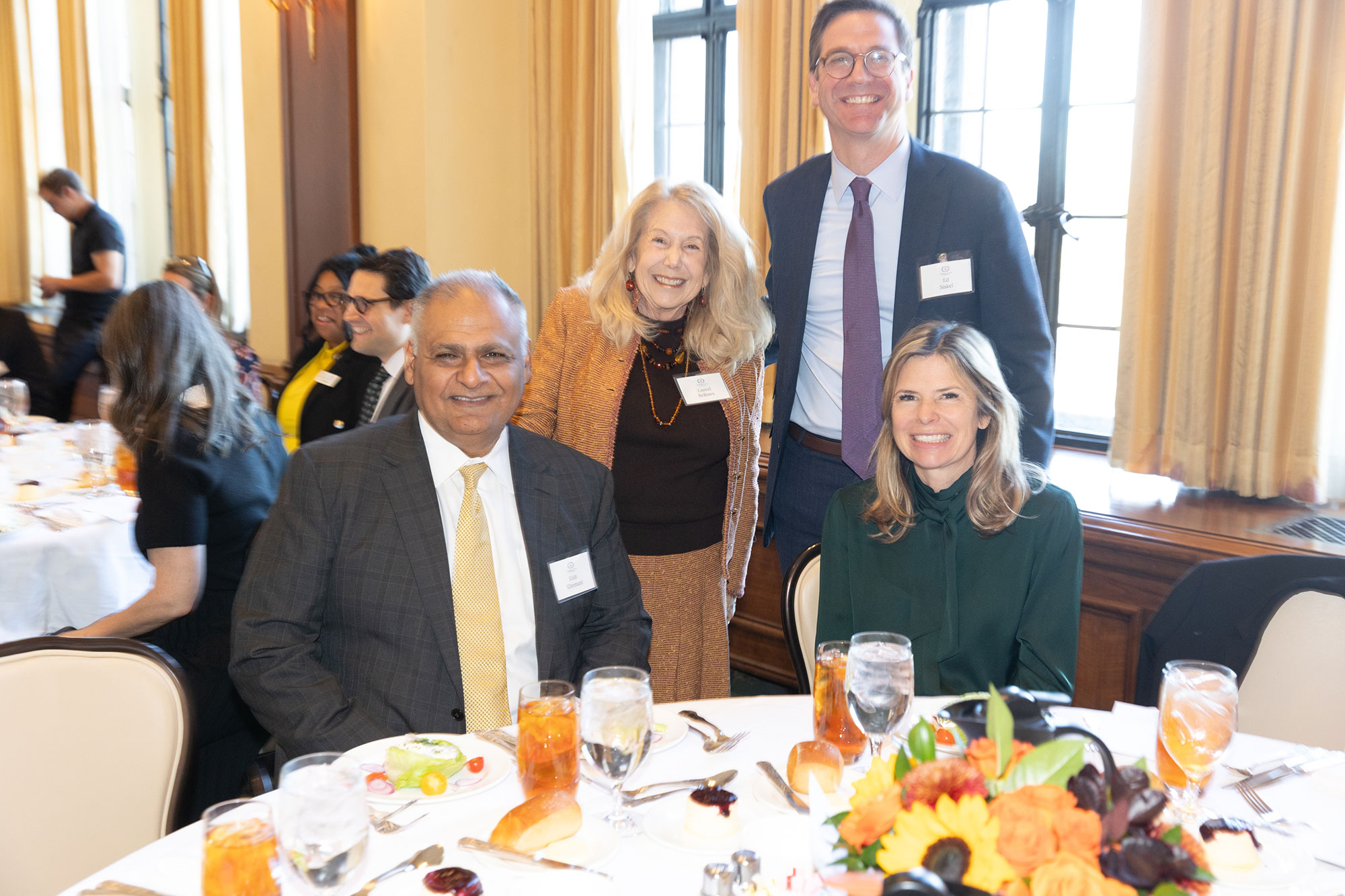 Four people pose together around a table