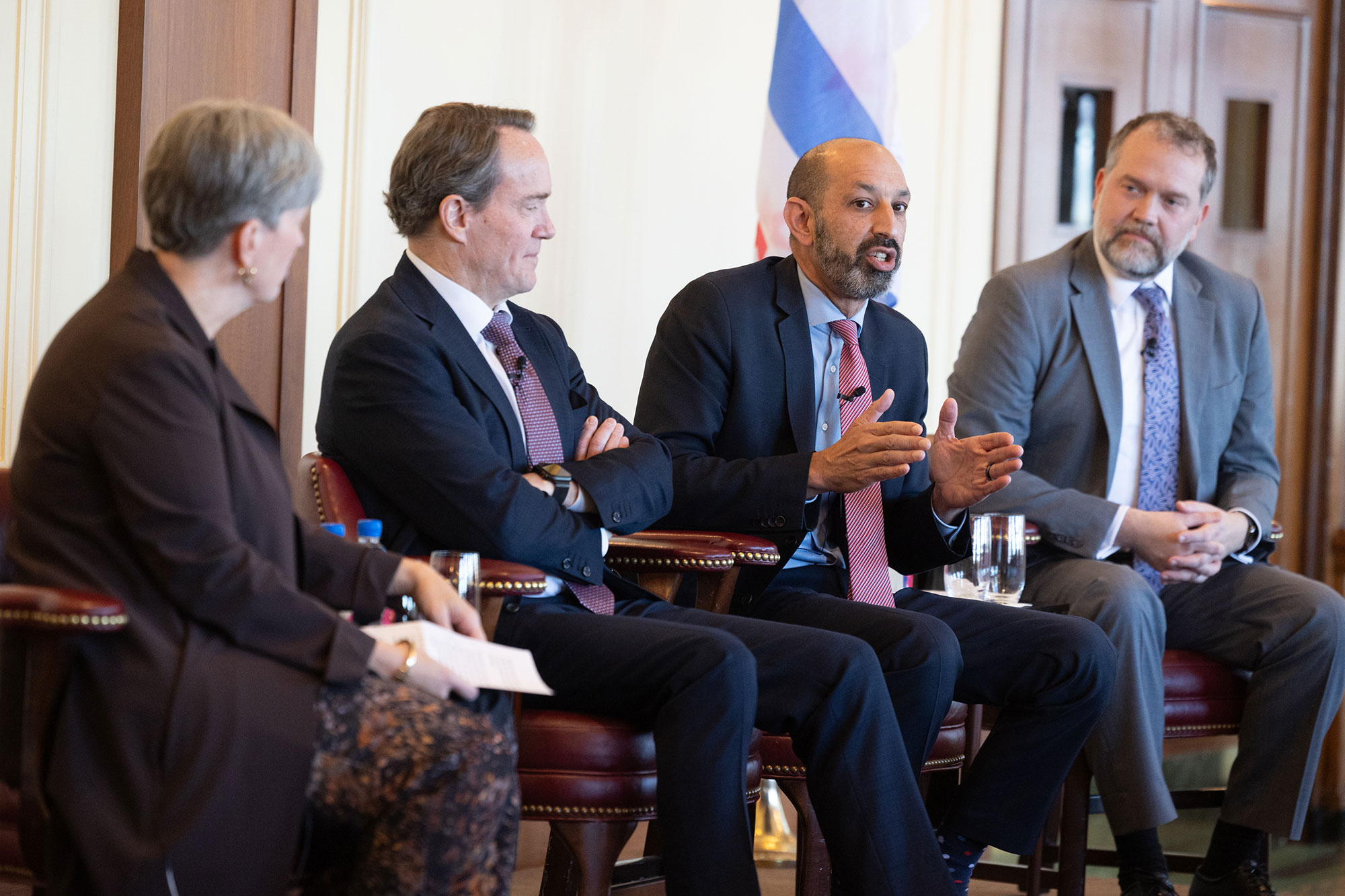4 people talk on stage while sitting in chairs