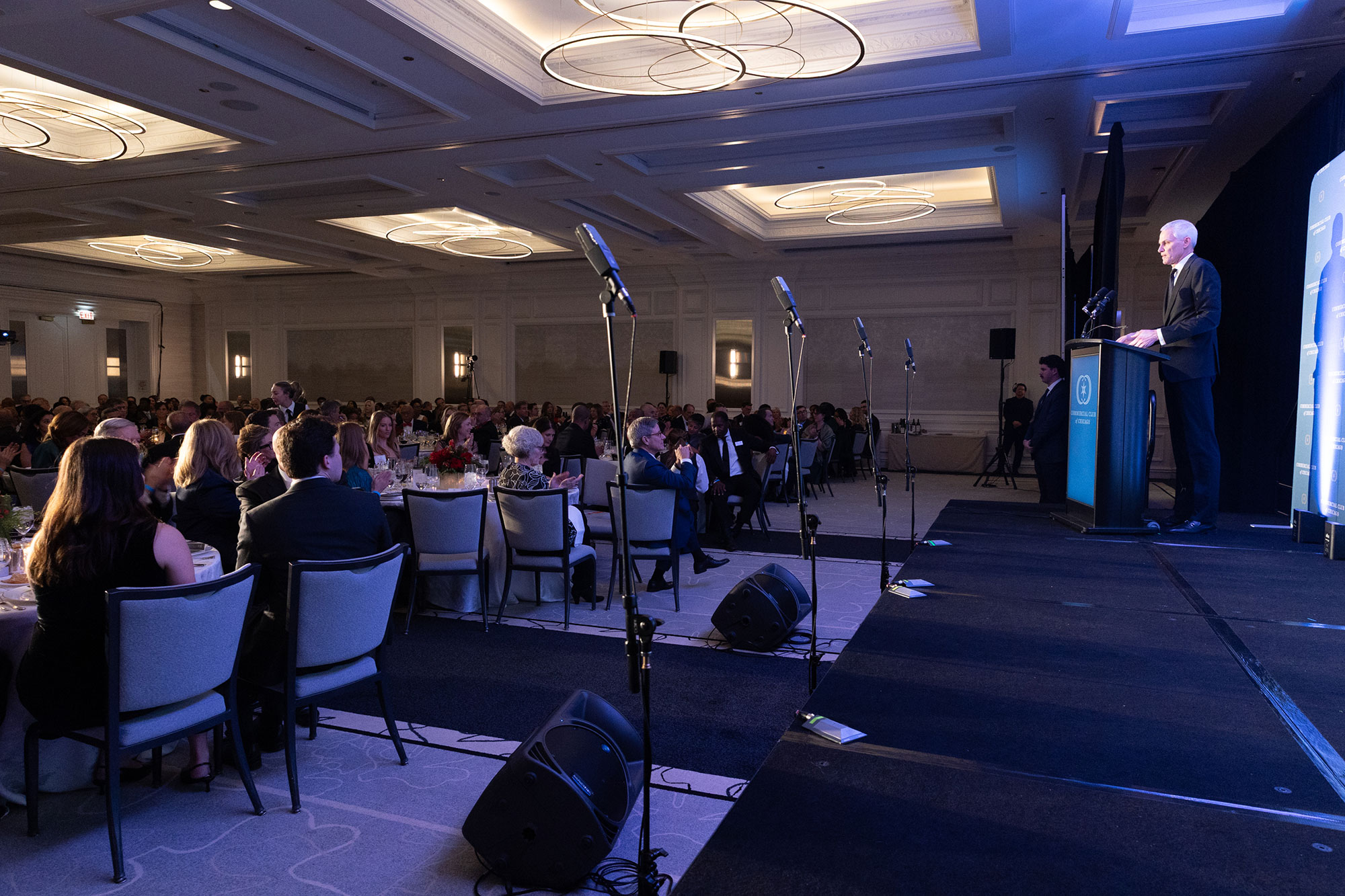 A person stands behind a podium on-stage in front of an audience