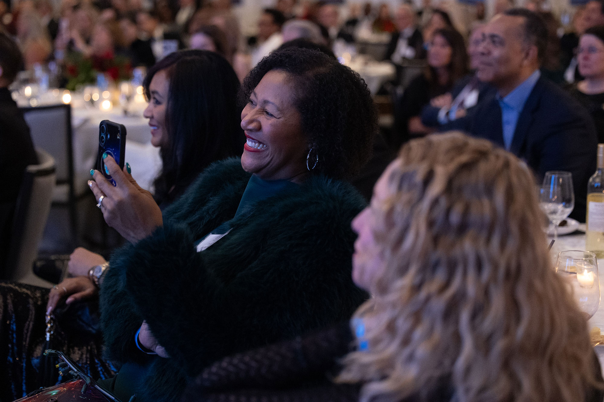 A person in the audience laughs while holding a mobile phone