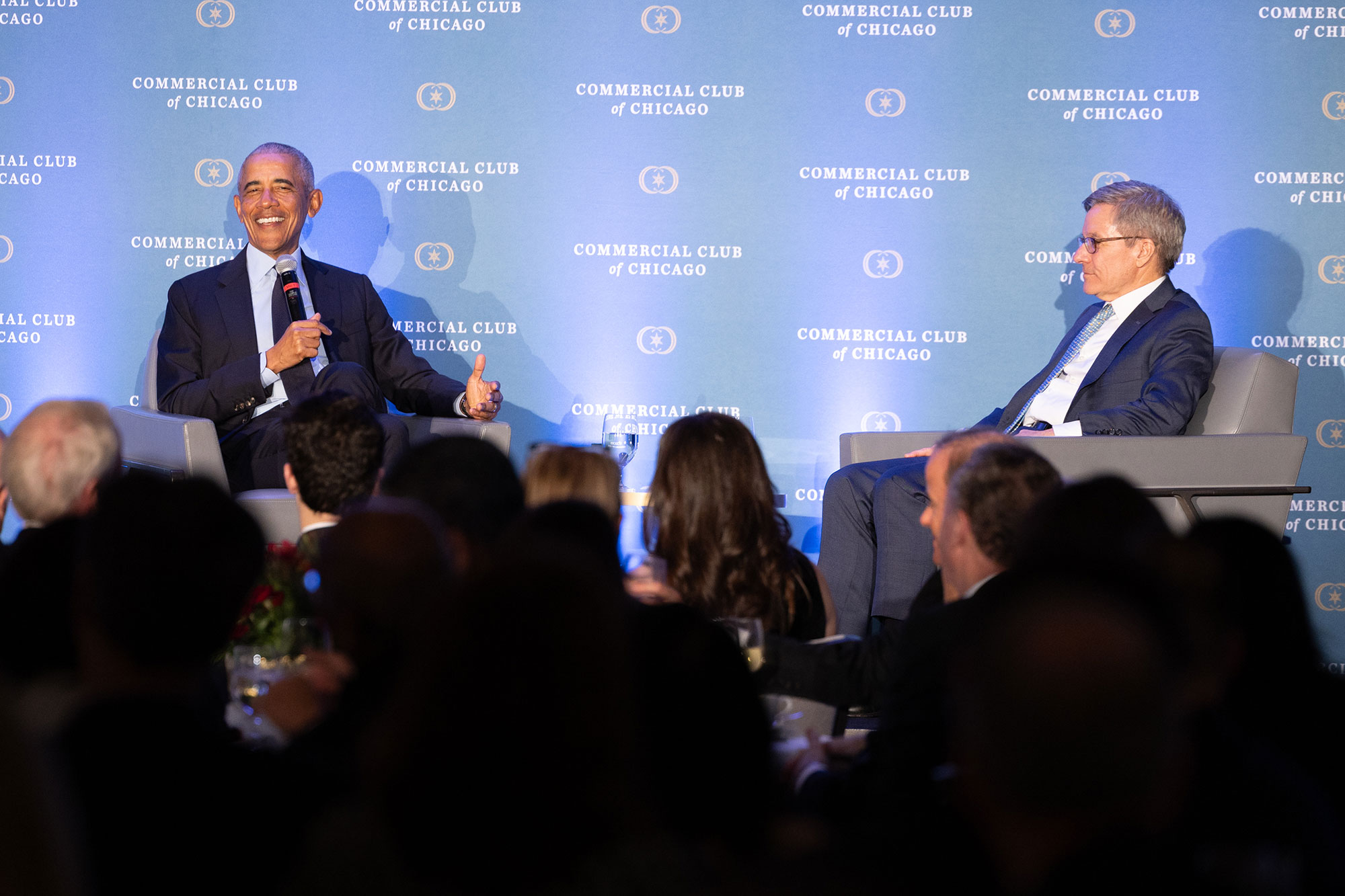 President Obama laughs while holding a microphone