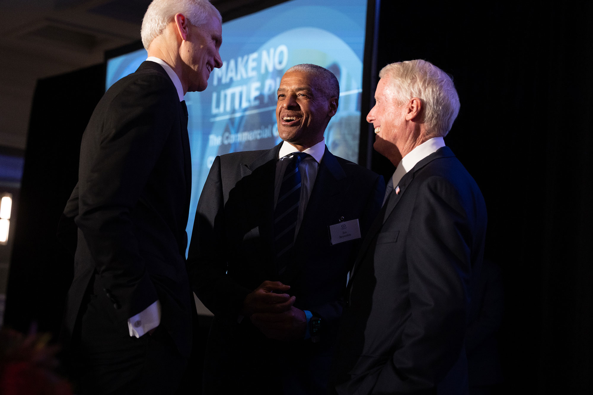 Three people stand together talking