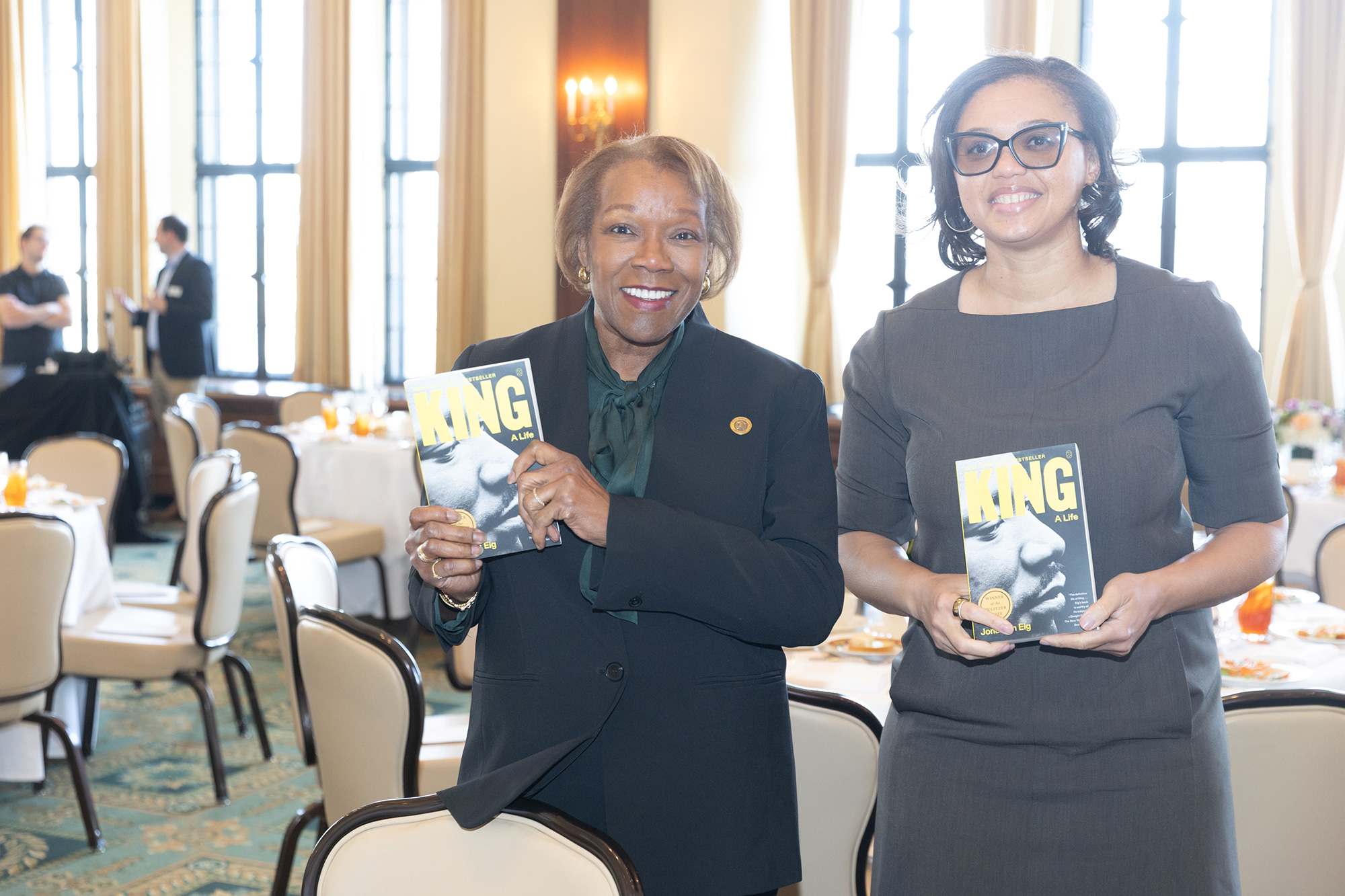 Two people stand while holding books