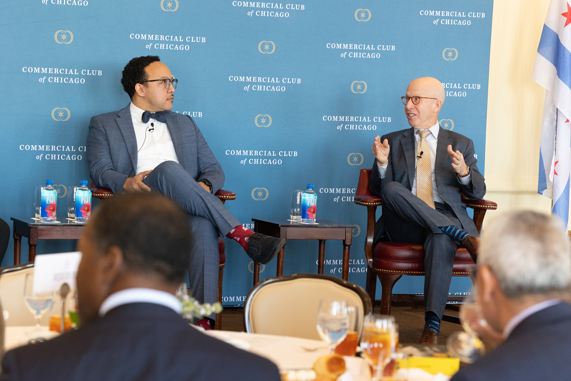 Two people sit in chairs while talking on stage