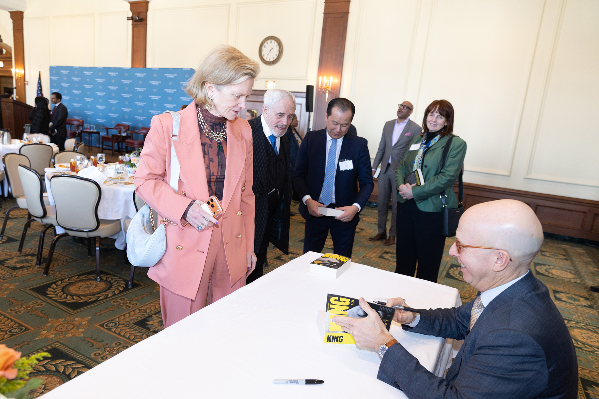 People stand in line while someone signs a book
