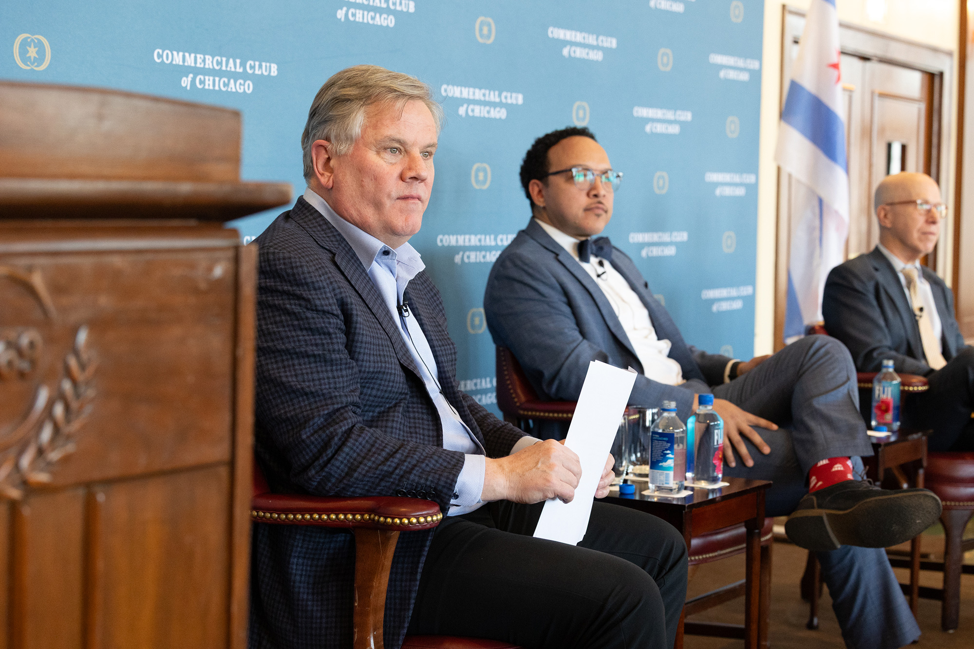 Three people sit on stage in front of a podium