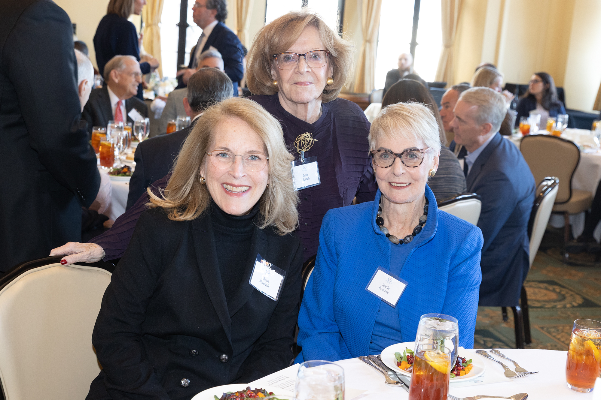 Three people pose together while sitting at a table