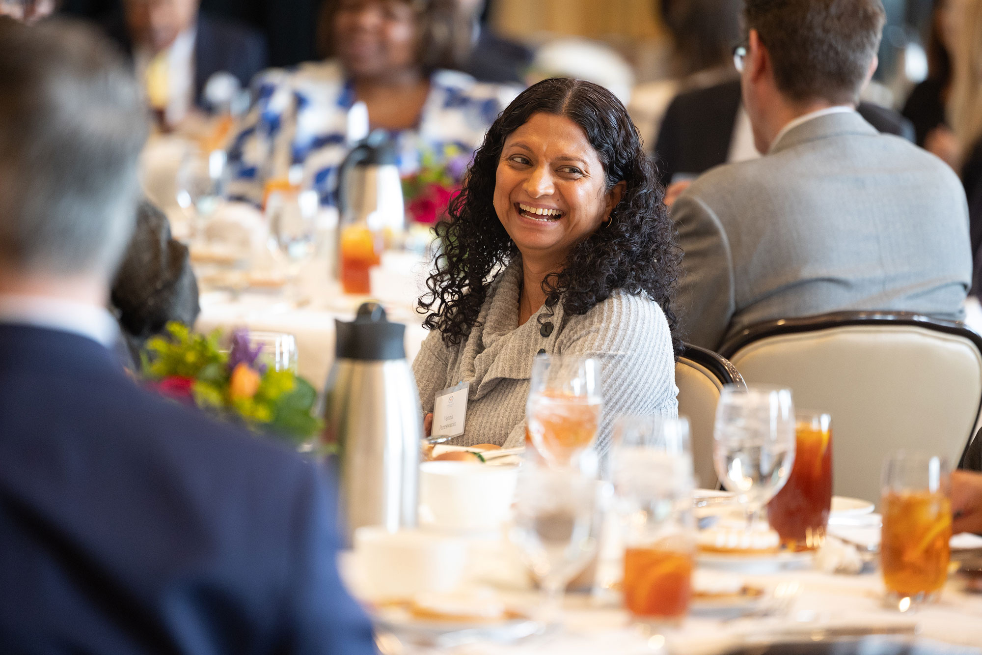A person in the audience at a table laughs